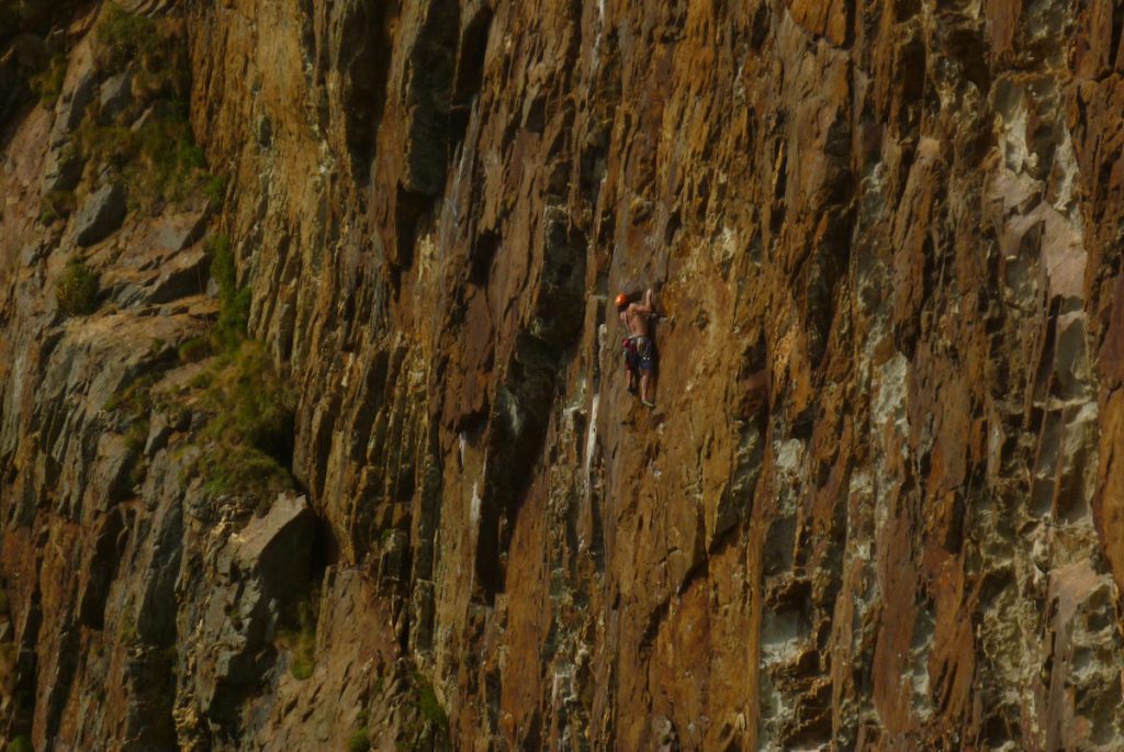 A climber tackles the emotional Blue Remembered Hills on Right Hand Red Wall, South Stack Area, Gogarth. This route is two long and demanding pitches, the first sustain, the second features a mind-bending move to reach a large falke followed by loose tottering.
