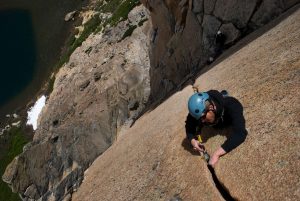 A rock climber placing a cam in a perfect granite crack in Frey, Argentina